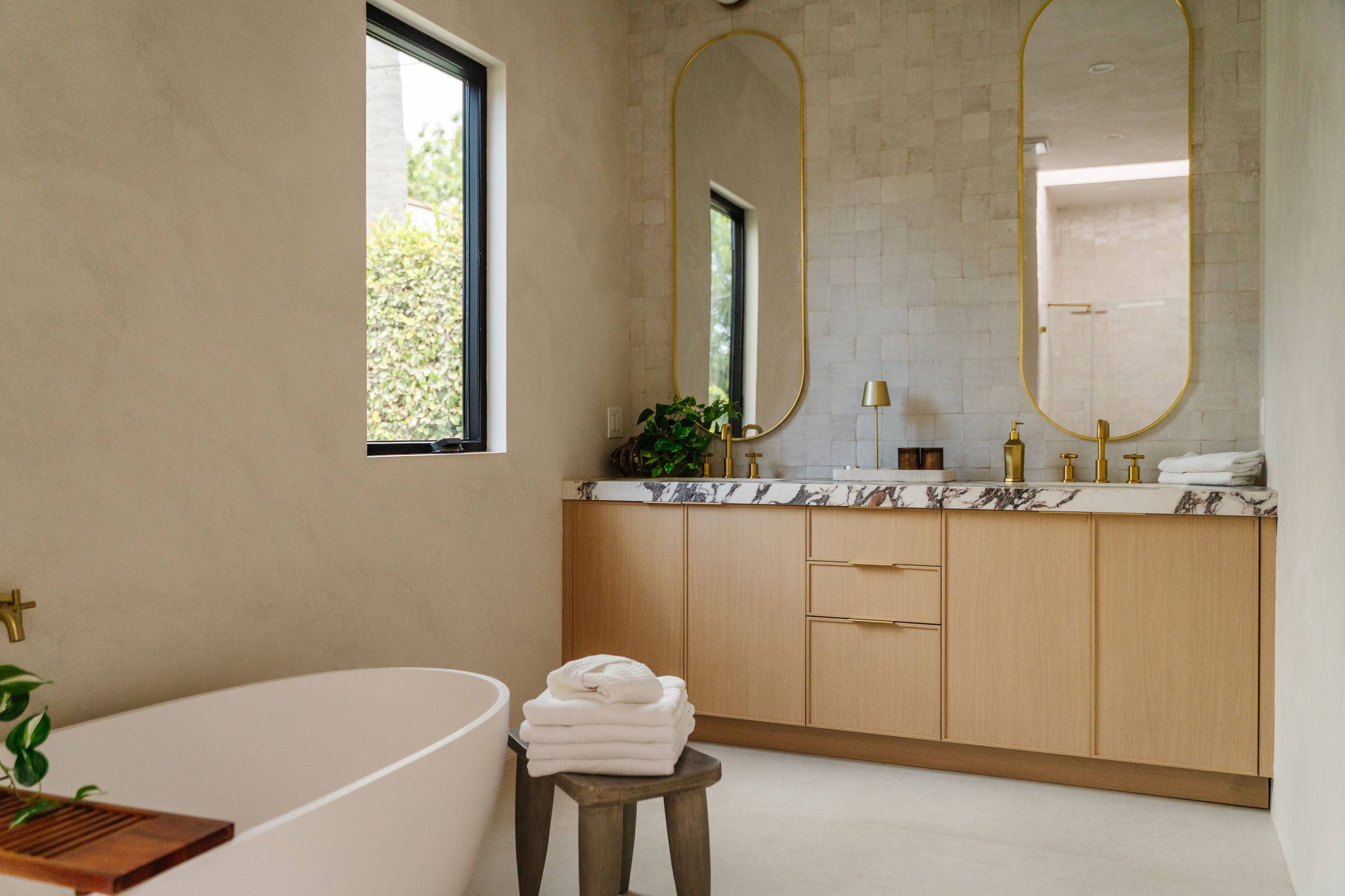 Echo Park bathroom with a light oak double vanity, marble counter, and brass-framed mirrors