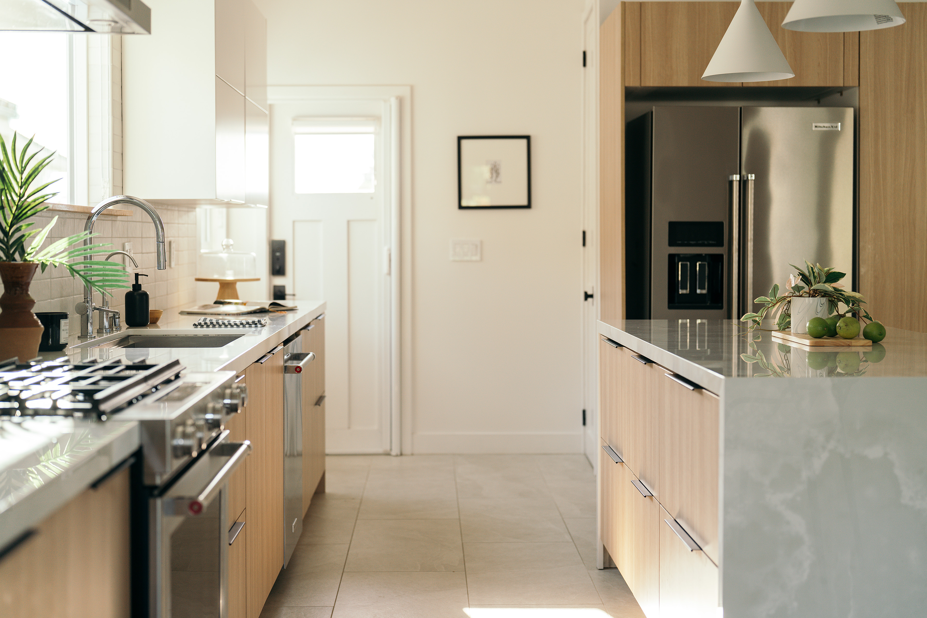 Galley view of the West Hollywood kitchen with marble counters and wood cabinetry