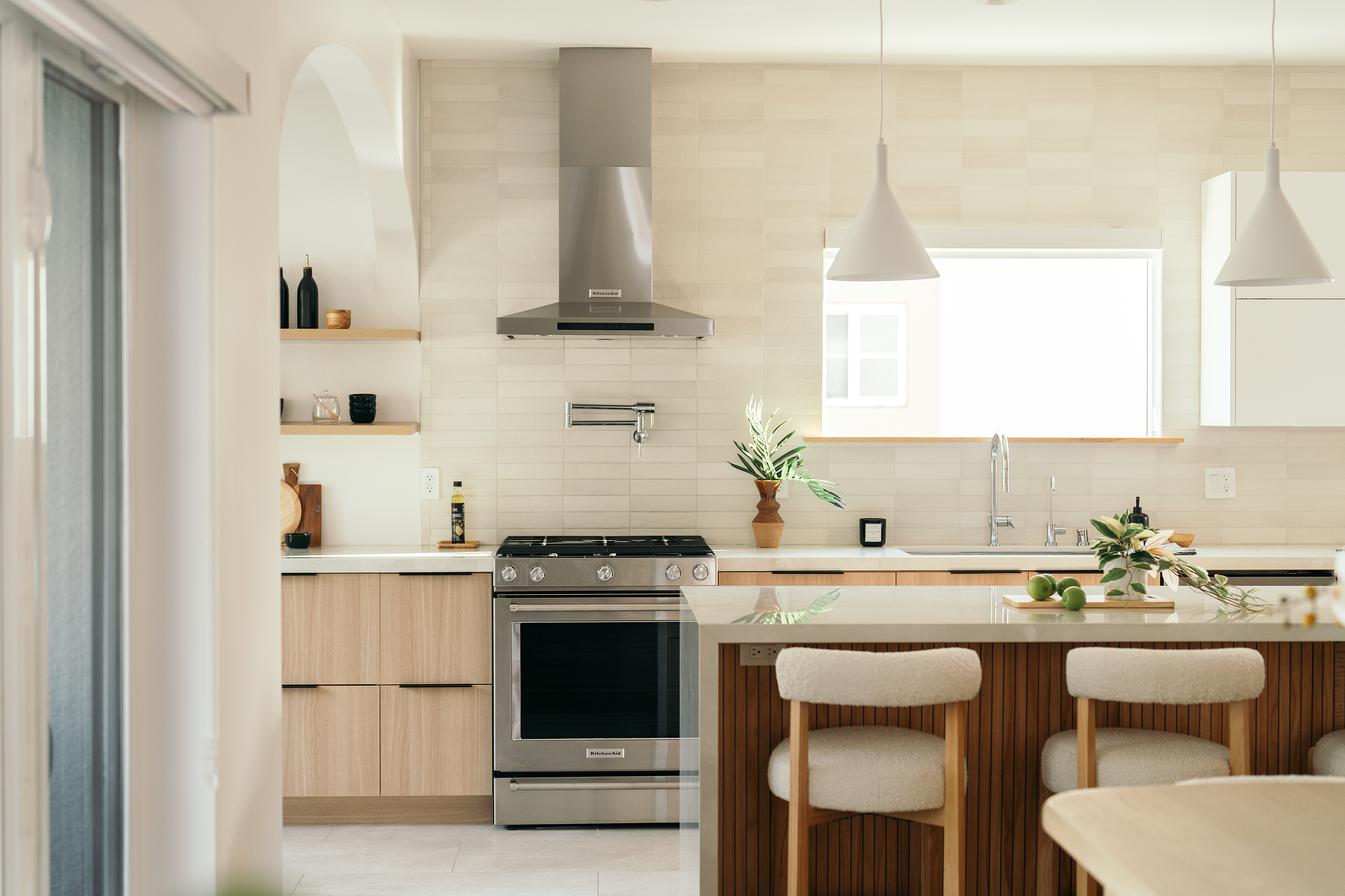 Light wood kitchen with range, tiled backsplash, and peninsula seating