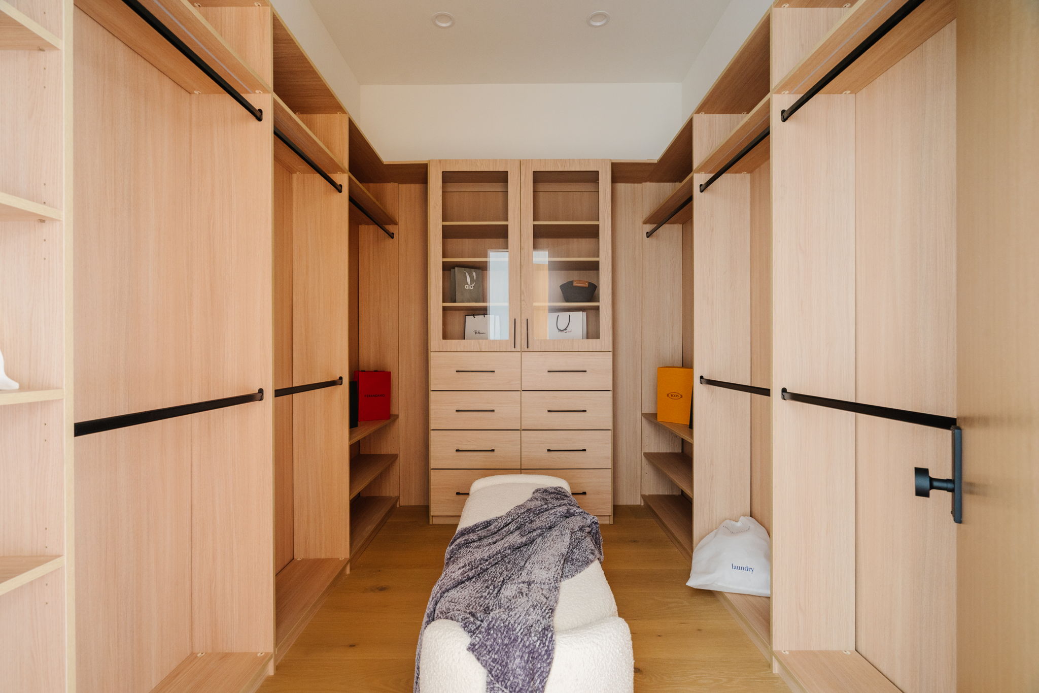 Willow walk-in closet with light oak built-ins and a central bench